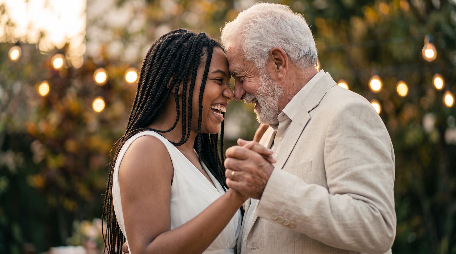 Noiva de tranças dançando com o avô na festa de casamento, os dois rindo de testa colada